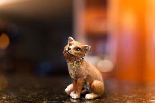 A closeup of an adorable little statue of a fox on a black table