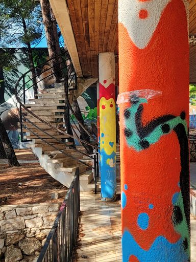A vertical shot of the stairs in the background of the graffiti painted poles