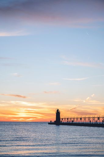 A vertical view of a lighthouse overlooking a beautiful seascape at scenic sunset