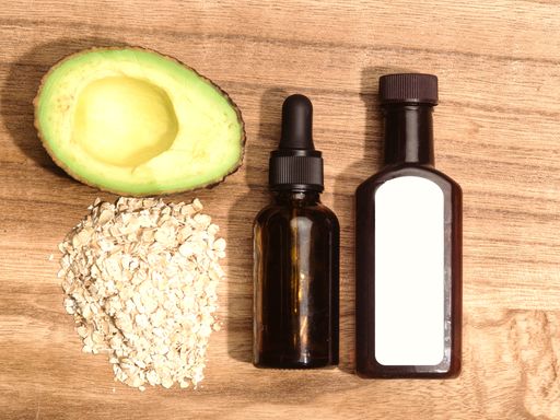 The two bottles of skincare serums with oat flakes and avocado nearby, a closeup shot