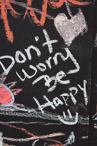 A vertical shot of 'Don't worry be happy' written on a blackboard