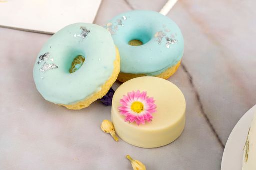 A top view of a wooden table with donuts and cake decorated with a dried flower