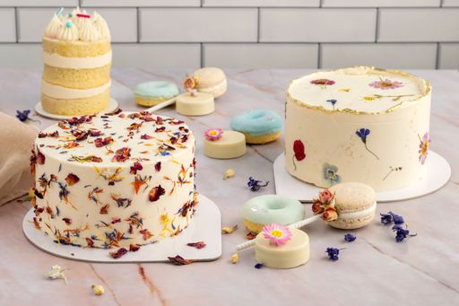 A wooden table with cakes and sweets decorated with dried flowers and delicious colorful cream