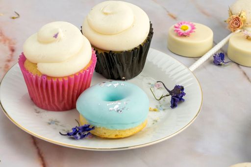 A top view of a wooden table with donuts and cupcakes decorated with dried flowers