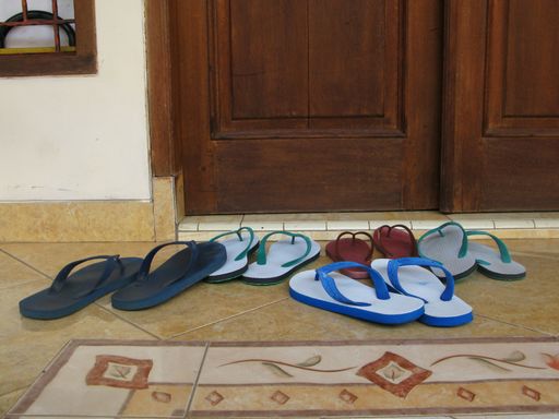 A Pile of slippers in front of door that marks the presence of guests in the house