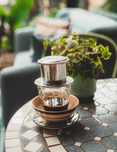 Vietnamese coffee with condensed milk in glass cups and traditional metal coffee maker phin. Traditional method of making of vietnamese coffee