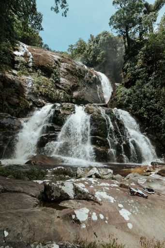 A vertical shot of a scenic waterfall surrounded by lush greenery, cool for background