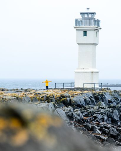 A vertical shot of a person near a white lighthouse