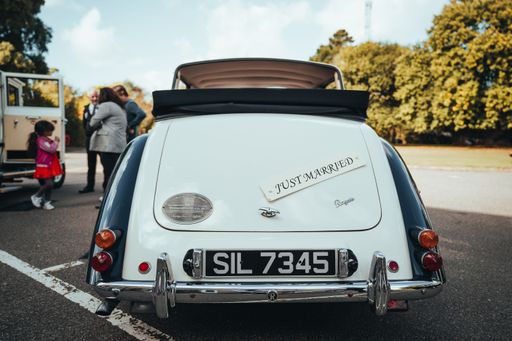 A view from behind of a classic wedding car parked in the lot on a sunny day