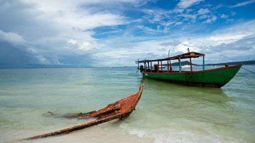 A boat in the open blue sea under the white cloudy sky.