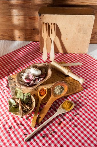 A closeup of wooden kitchen utensils, garlic, bay leaf and spices