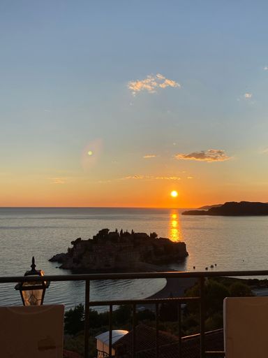 A vertical shot of a balcony overlooking a sea during sunset