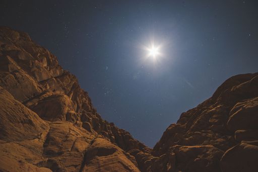 A scenic view of huge canyons in the desert under the starry sky with the shining moon