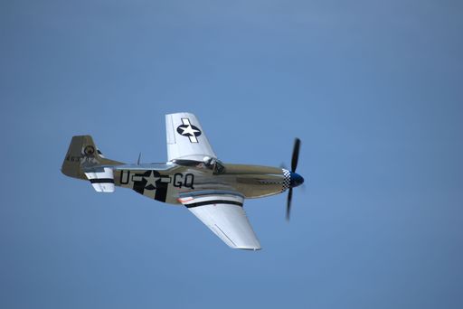 The WWII North American P-51 Mustang making a banked turn over Springbank Airport in blue sky