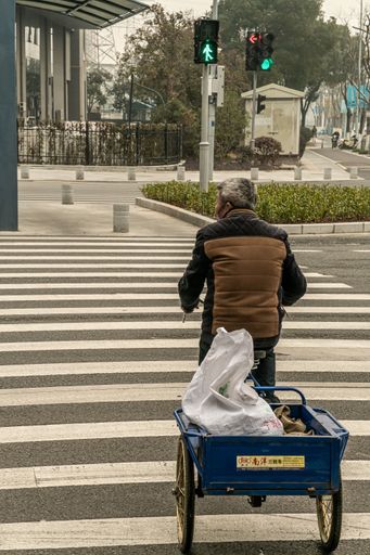 An elderly person crossing a street o his tri-bike in Ningbo, China