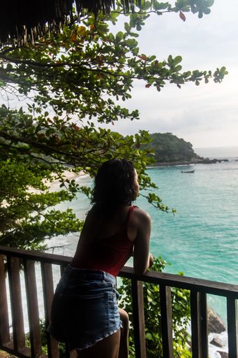 A vertical shot of a female wearing shorts over a swimsuit admiring the ocean view