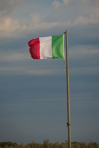 Large Italian flag waving in the wind at sunrise. Vertical photo.