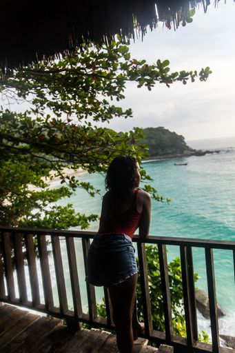 A vertical shot of a female wearing shorts over a swimsuit admiring the ocean view