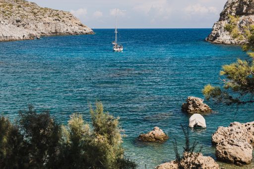 A beautiful boat swimming in a sea with huge rock formations on a sunny day