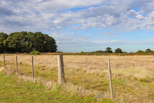 A country landscape with a fence in a field under a cloudy sky