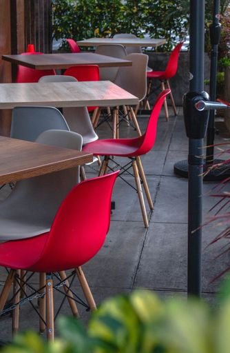 A vertical shot of red and gray chairs set up by square tables in an outdoor restaurant in Chimbote