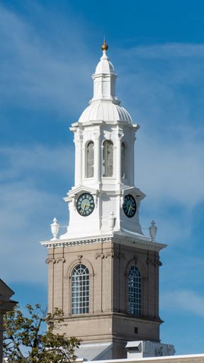 A vertical shot of the clock tower of Hayes Hall in the University at Buffalo under a bright blue sky
