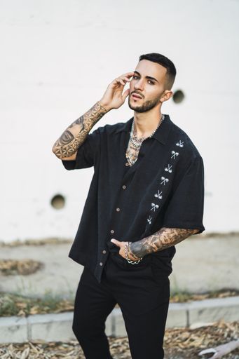 A vertical shot of a young Caucasian man with tattoos posing