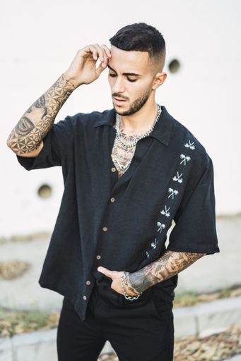 A vertical shot of a cool European male with tattoos posing with a building background
