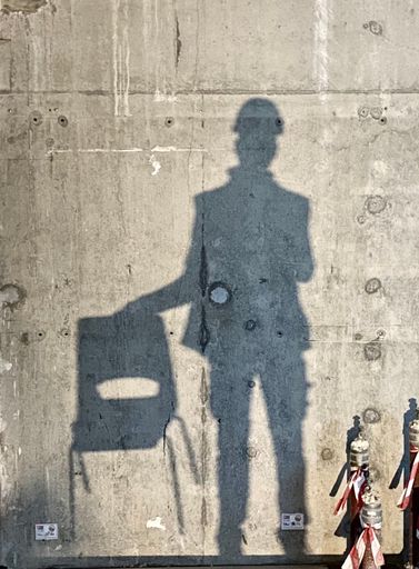 A vertical shot of a shadow of a construction worker holding a chair