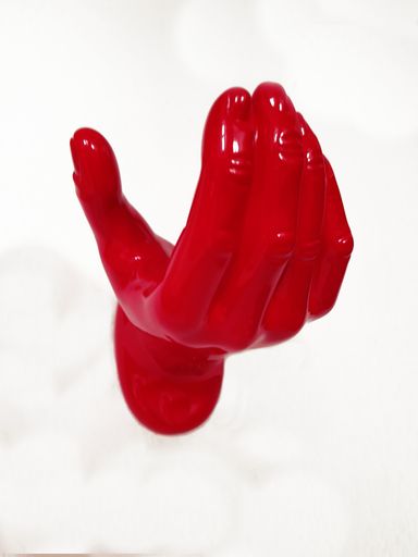 A vertical shot of a red plastic hand on a white wall