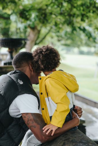 A vertical shot of an African-American child and his father in the park