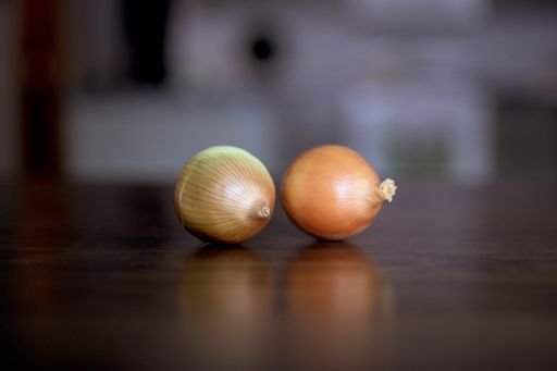 A closeup shot of two onions on a wooden surface with a blurred background