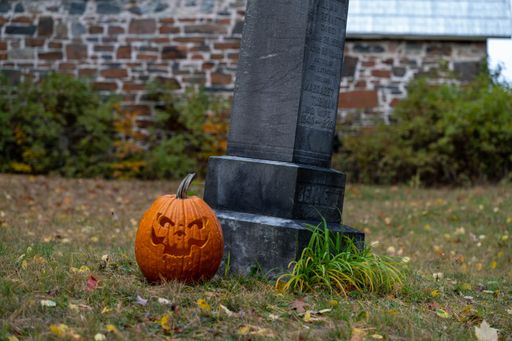 The curved pumpkin on the grass near the grave for Halloween celebration