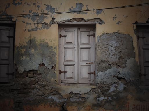 A beautiful view of a wooden window in the shape of a door on an old wall