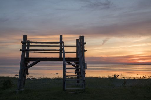 A closeup of an old small wooden deck at a beach surrounded by the sea during the sunset