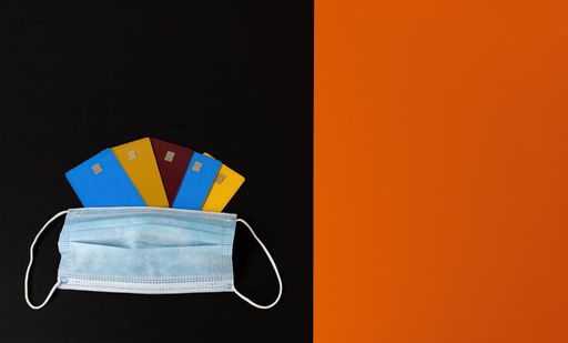 A high angle shot of colorful credit card holders on the table with a facemask on it