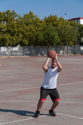 A vertical shot of a young male playing basketball in a sports ground