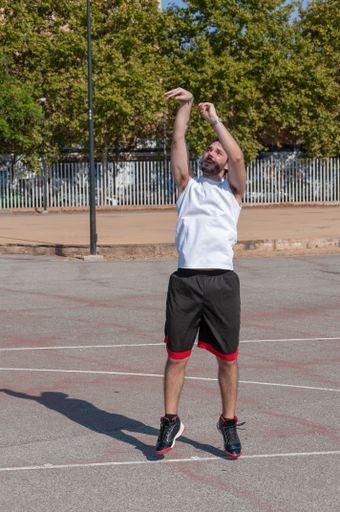 A vertical shot of a young male playing basketball in the sports ground
