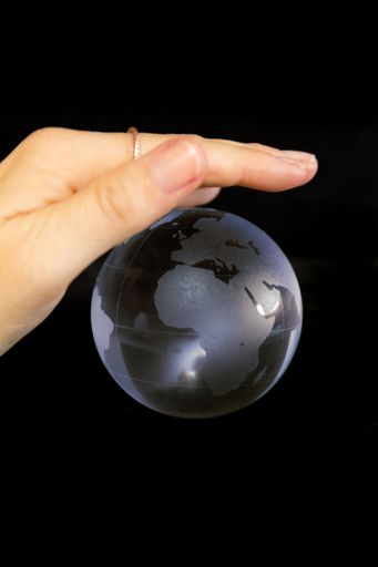 A vertical shot of a woman holding a small globe on the black background
