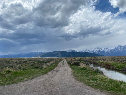 A dirt road with mountains in the background against a cloudy sky in Wyoming, USA