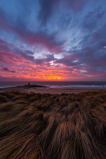 A breathtaking vertical shot of the colorful sunset sky over the shore of Vlissingen