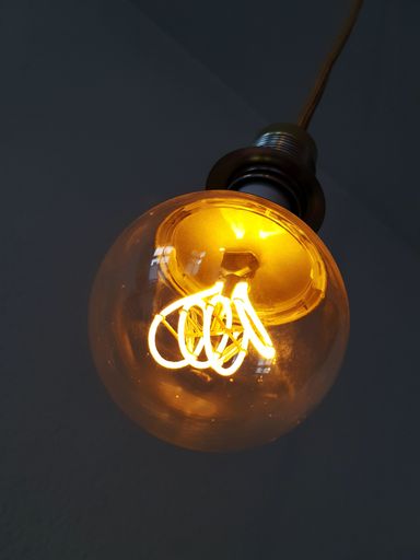 A vertical shot of a light bulb against a dark background