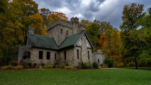 A field with an old traditional castle surrounded by autumn trees in the background