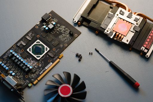 A top view of disassembled graphics card XFX GPU AMD fan screws screwdriver on a table