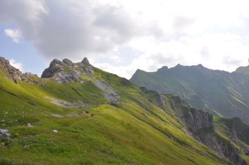 A mesmerizing landscape of a steep slope covered by grass with mountains in the background