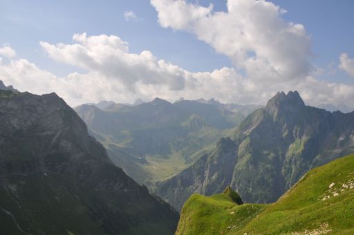 A mesmerizing landscape of a steep slope covered by grass with mountains in the background