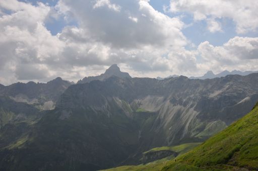 A mountain range, with rugged rocky mountains and steep slopes covered by grass