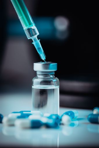 A vertical shot of pharmaceutical syringe with needle in a medicine and medical pills - illegal doping drugs in sport