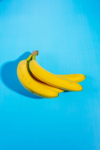 A vertical shot of Yellow bananas isolated on light blue background
