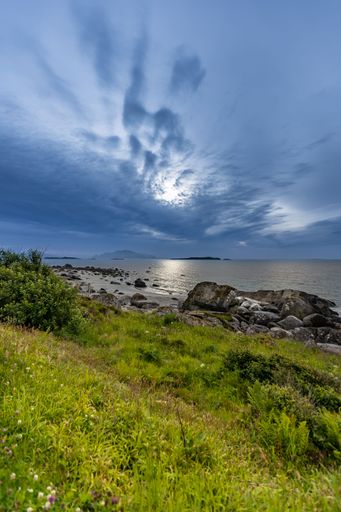 A vertical shot of a blue sunset sky over a rocky seashore in Norway